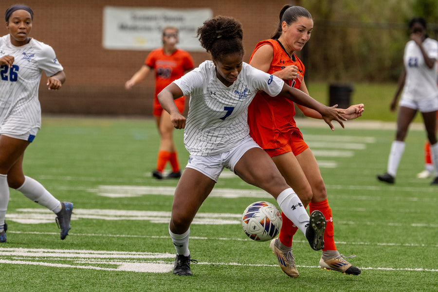 Soccer players in action on a field with a goalpost in the background