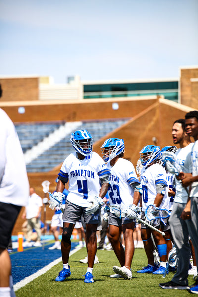 Athletes in sports uniforms on a field with a building in the background