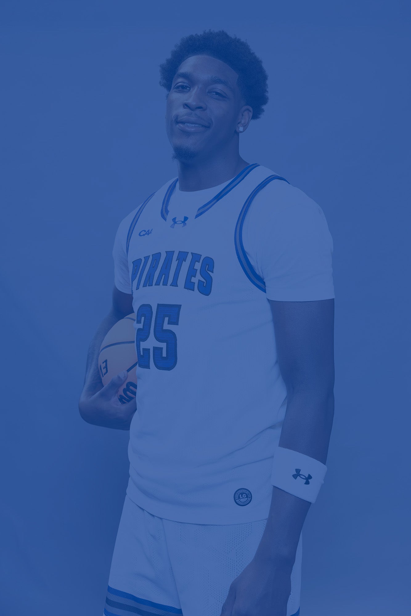 Hampton University basketball player in white Pirates uniform holding a basketball against a light background with a blue color overlay.
