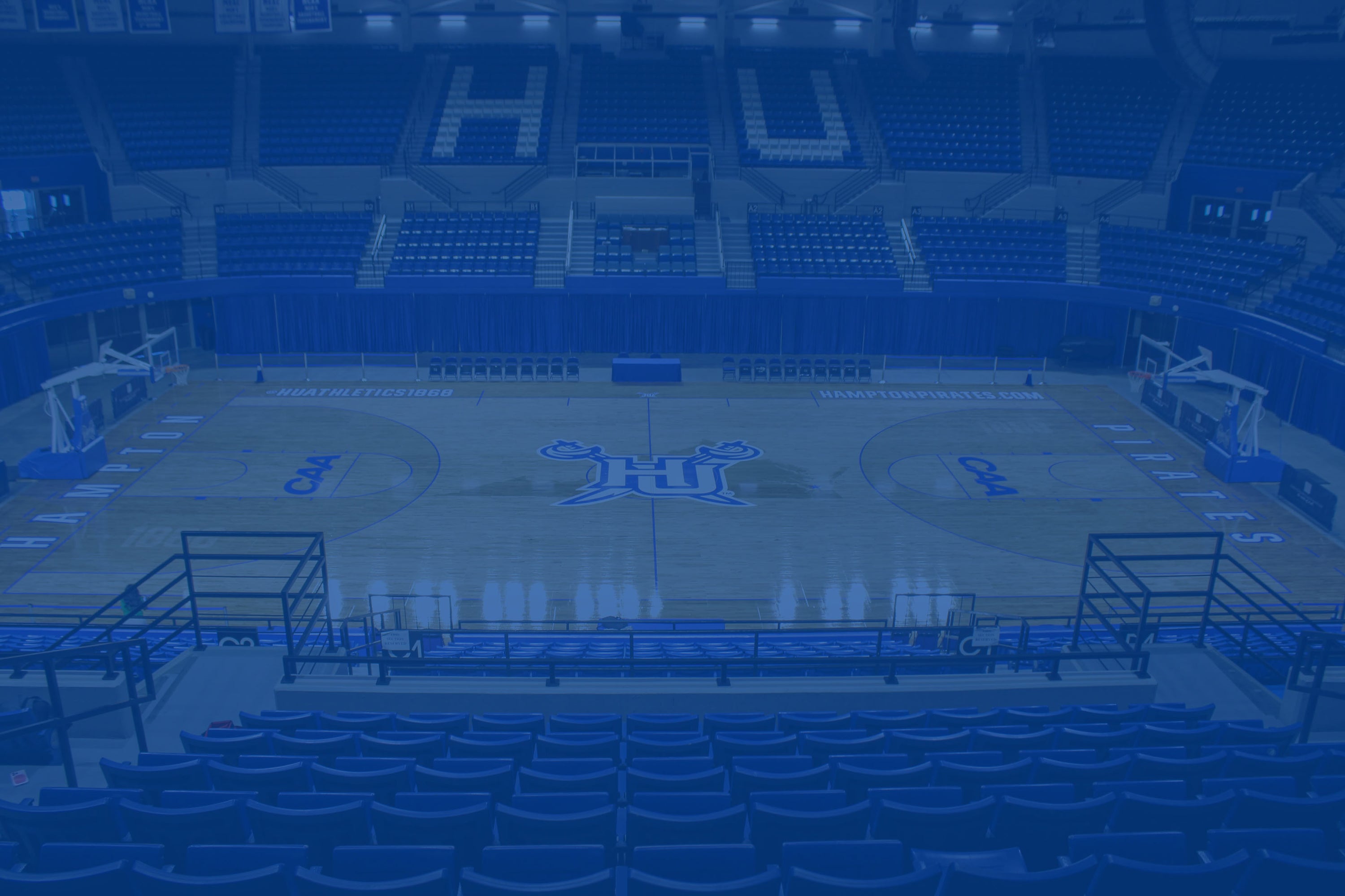 Basketball court with 'HU' branding in a stadium setting. The image has a blue color overlay.