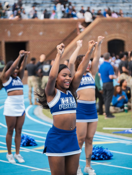 Cheerleaders in blue and white uniforms with 'HU Pirates' on a track and field event.