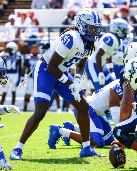 Football player in blue and white uniform on field with teammates and opponents