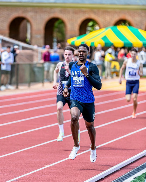 HU student-athlete running on a track with a blue uniform and number 424, surrounded by other runners and spectators.