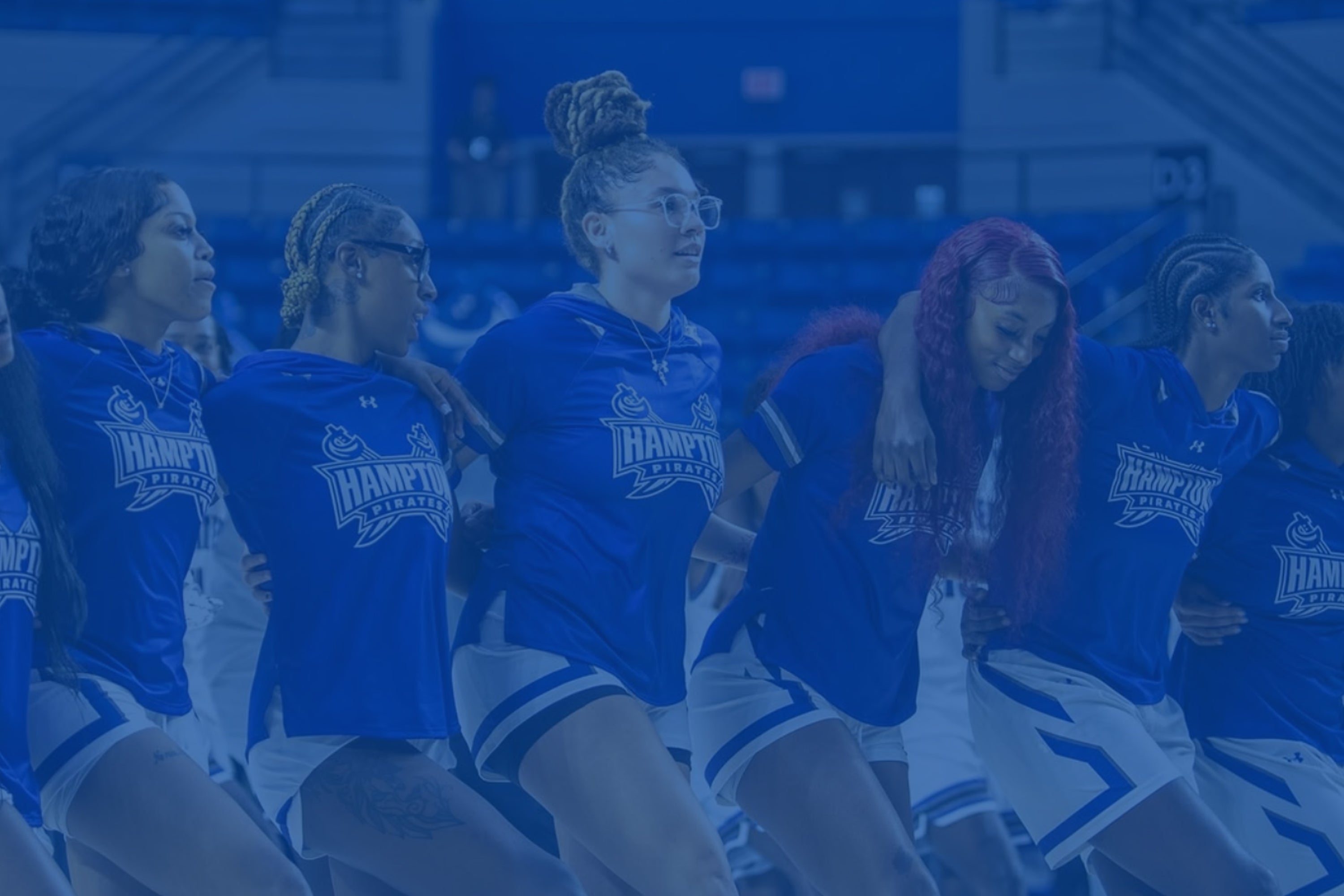 Group of women in blue sports uniforms with 'Hampton' logo on a blurred background