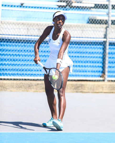 Hampton University women’s tennis player returning a shot during a match on an outdoor court.